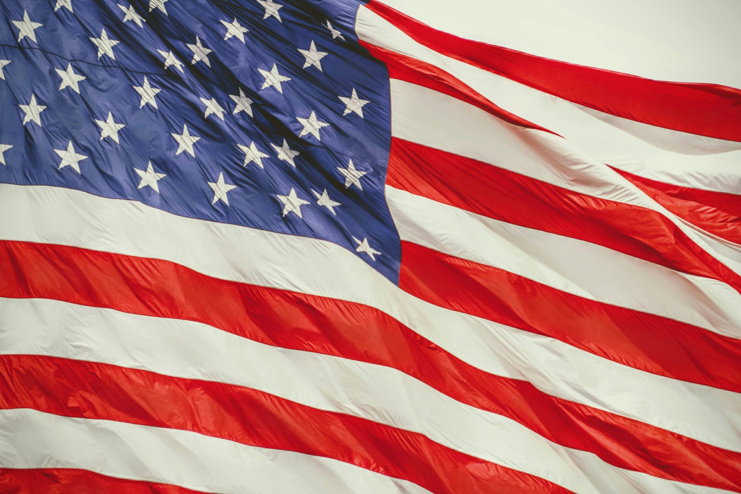 An American flag waving against an off-white background.