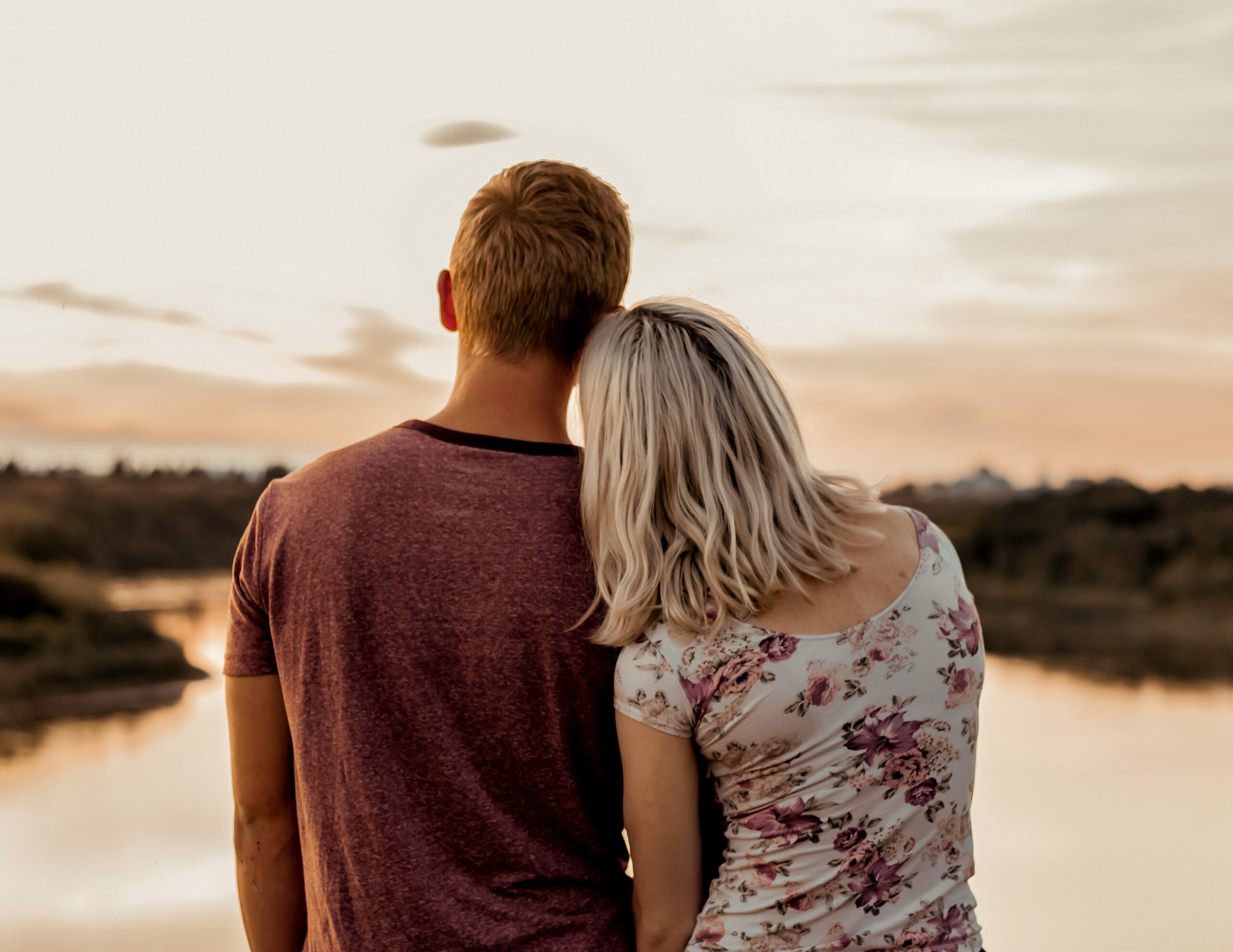A male-female couple facing away from the camera holding hands with the woman's head on the man's shoulder