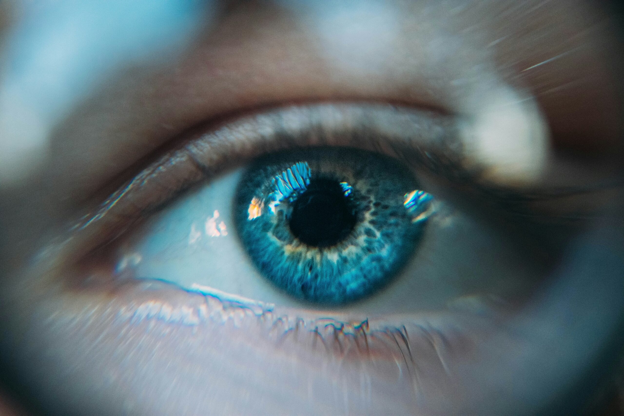 A close up image of a blue eye with cool tones and distorted bits of light
